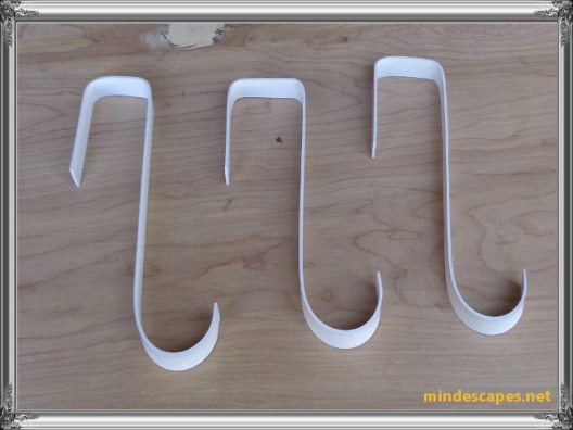3 hooks painted white laying on wooden board