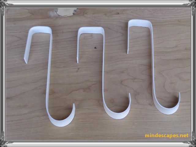 3 hooks painted white laying on wooden board